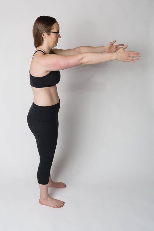 Jessie stands facing to the side, demonstrating a "bum tucked" body position with her arms extended straight out in front of her, and her tailbone tucked under her hips. This image is part of an explanation about how body positions relate to healing diastasis recti.